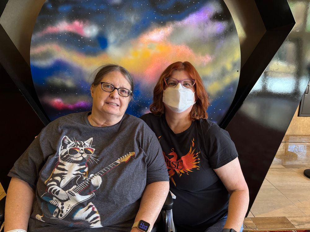 Two women in front of a picture of a planet