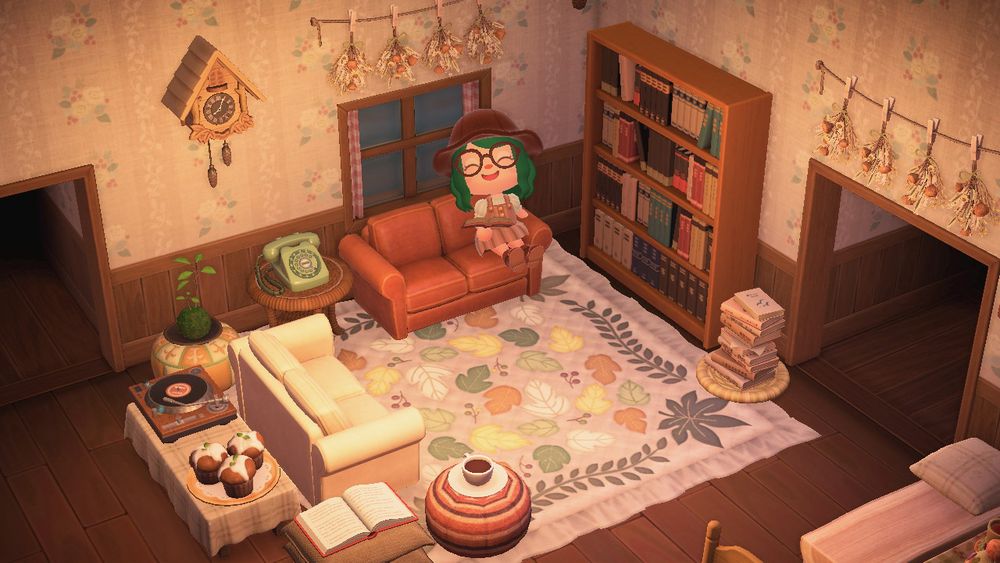 lohla’s animal crossing character sits on the couch in their living room with a book