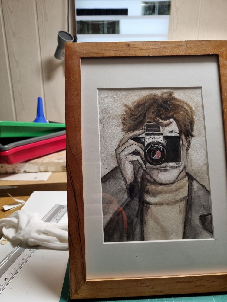 Fertiggerahmtes Bild des Fotografen. Im Hintergrund Fotolaborsachen.