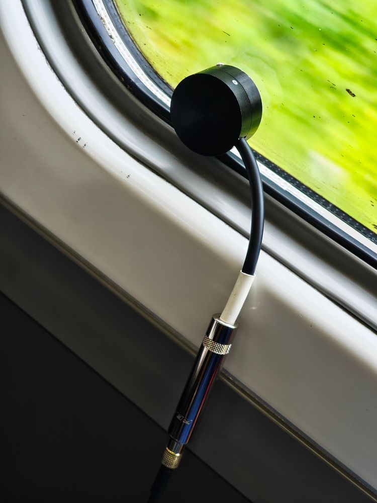 A contact microphone stuck to a train window on the inside