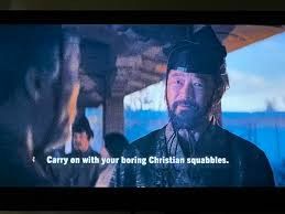 A frame from the recent remake of Shogun, with Todanobu Asano (as Kashigi Yabushige) facing the camera and the subtitle “Carry on with your boring Christian squabbles” across the frame. 