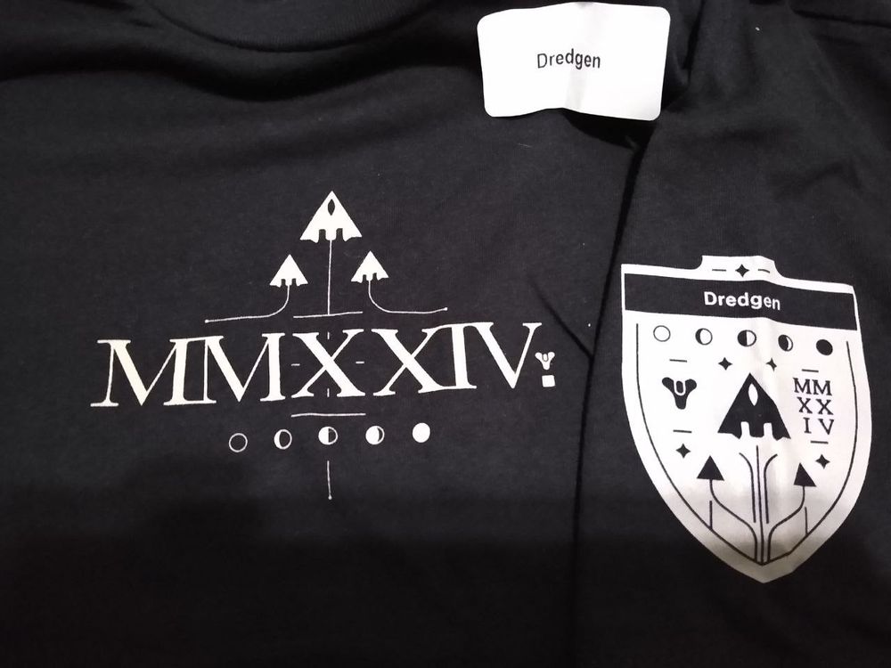 A black t-shirt from the Bungie game Destiny 2. It's for the Moments of Triumph 2024 event, with a cool logo showing roman numerals with the year in the center, ships taking off above it, and phases of the moon below it. On the shirt is a white sticker simply reading "Dredgen". On the sleeve is the Moments of Triumph emblem along with the title "Dredgen" on the badge where a name or gamer tag would normally be.