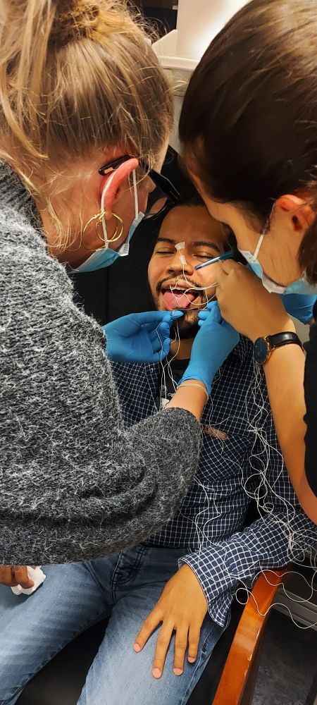 Someone is getting electrodes put on the tongue by two experimentaters 