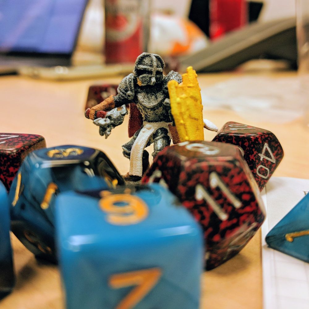 A minifig of a paladin standing amongst several TRRPG dice on a table.