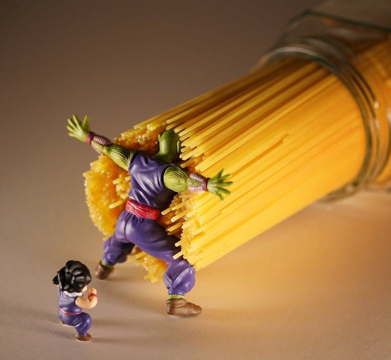 An adult action figure (Piccolo) shielding a child action figure from an onslaught of pasta noodles.