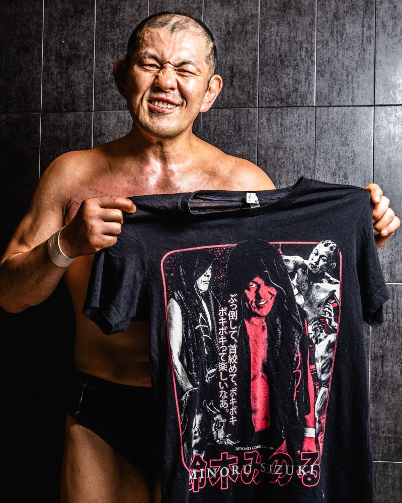 Minoru Suzuki holding a Minoru Suzuki graphic tee