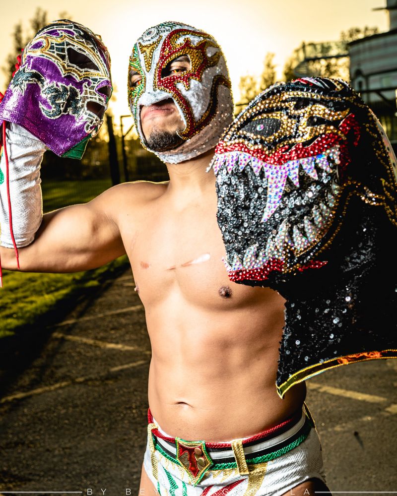 Cmll wrestler Titan holding two of his masks as the sun sets behind him