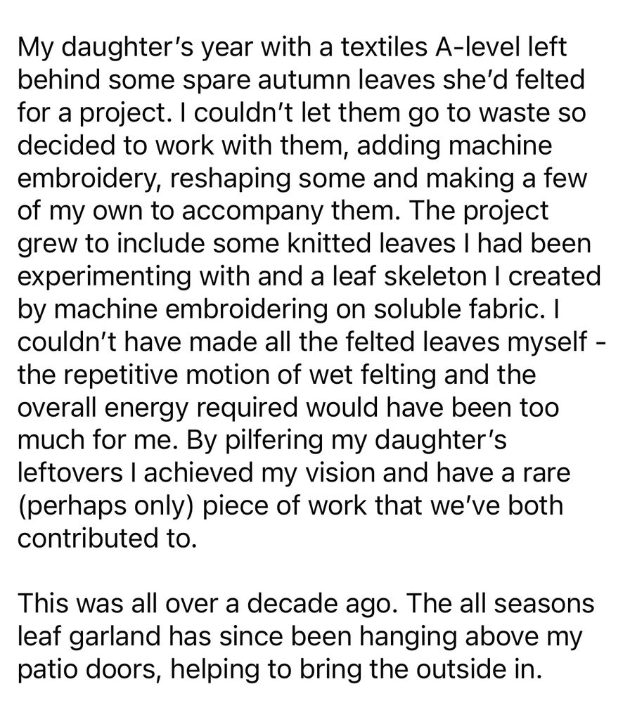 Black text on a white background reads:

My daughter's year with a textiles A-level left behind some spare autumn leaves she'd felted for a project. I couldn't let them go to waste so decided to work with them, adding machine embroidery, reshaping some and making a few of my own to accompany them. The project grew to include some knitted leaves I had been experimenting with and a leaf skeleton I created by machine embroidering on soluble fabric. I couldn't have made all the felted leaves myself - the repetitive motion of wet felting and the overall energy required would have been too much for me. By pilfering my daughter's leftovers I achieved my vision and have a rare (perhaps only) piece of work that we've both contributed to.
This was all over a decade ago. The all seasons leaf garland has since been hanging above my patio doors, helping to bring the outside in.