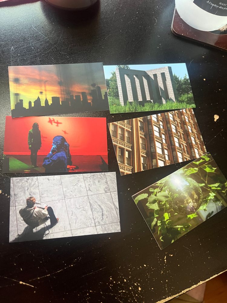 six business cards sitting on my desk. the cards are six different photos from across the years, including the fisher building in chicago, a disco ball in sunlight, the shadowy skyline of lower manhattan, a block sculpture in minneapolis, two girls lit in dramatic lighting, and a person reading a newspaper.