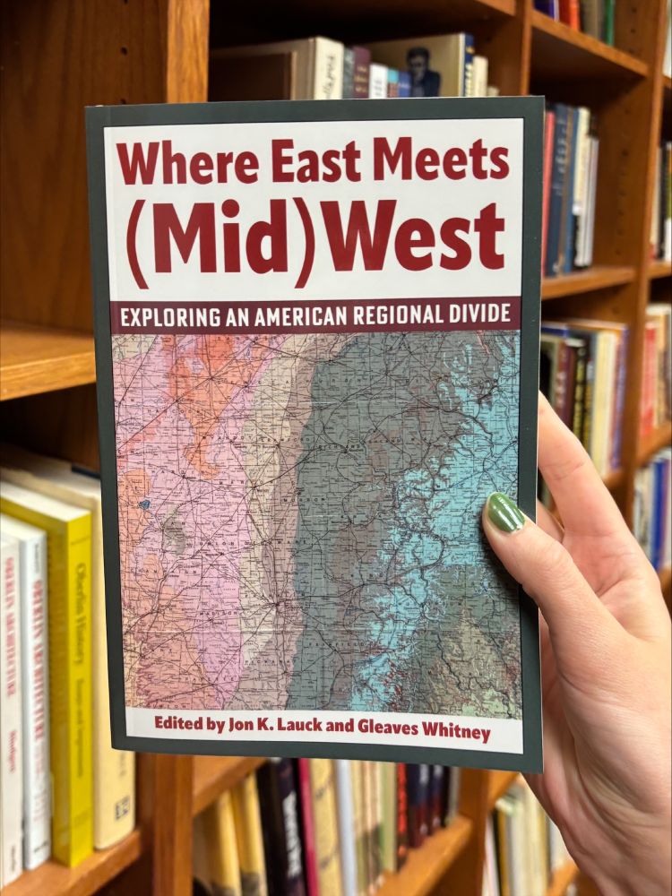 Book Where East Meets (Mid)West being held in a library.