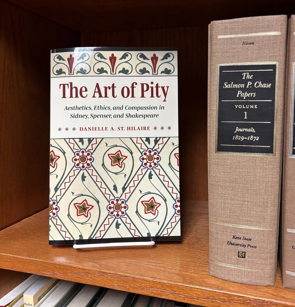 The Art of Pity on a bookshelf, face out.