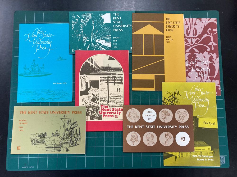 Multicolored seasonal catalogs from Kent State University Press on a cutting board background.