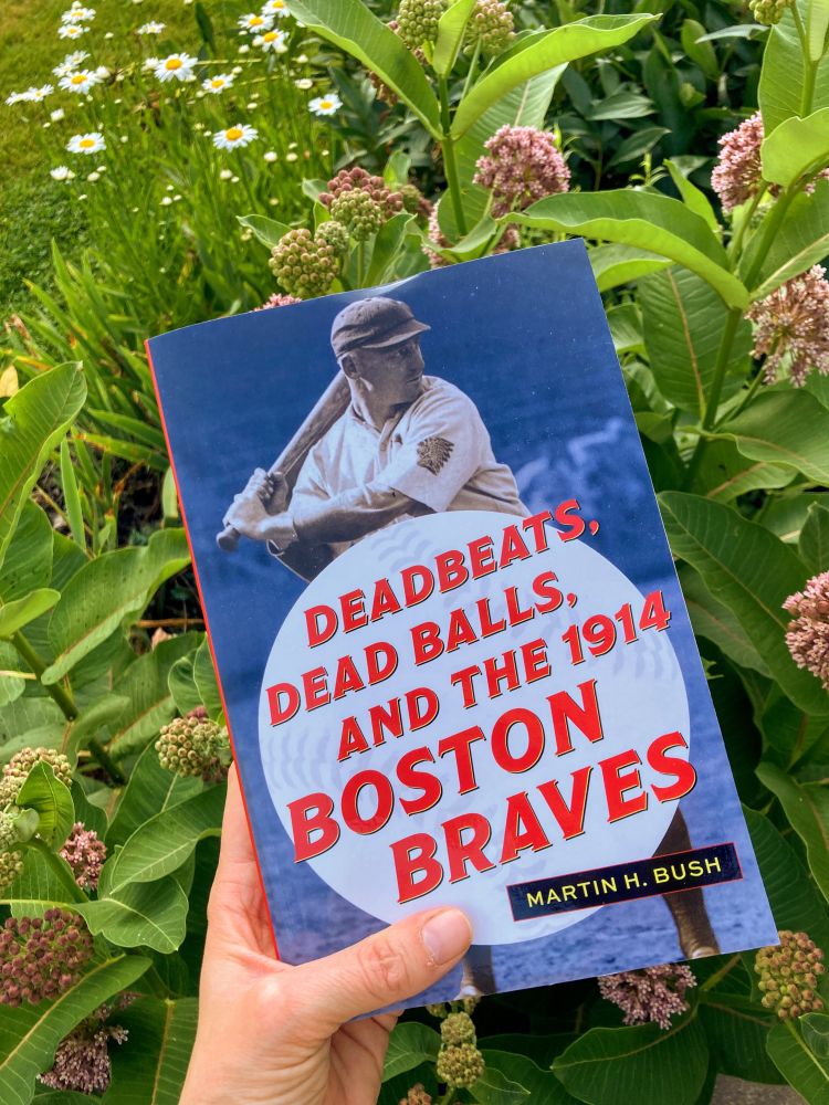 Deadbeats, Dead Balls, and the 1914 Boston Braves being held against a summery background.