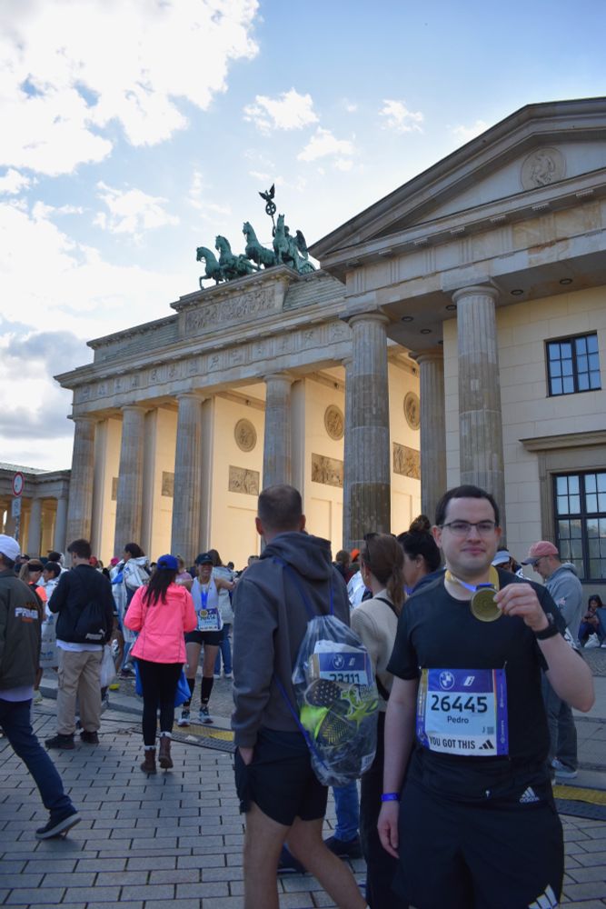 Photo of Pedro holding his medal in front of the Brandenburg Gate.