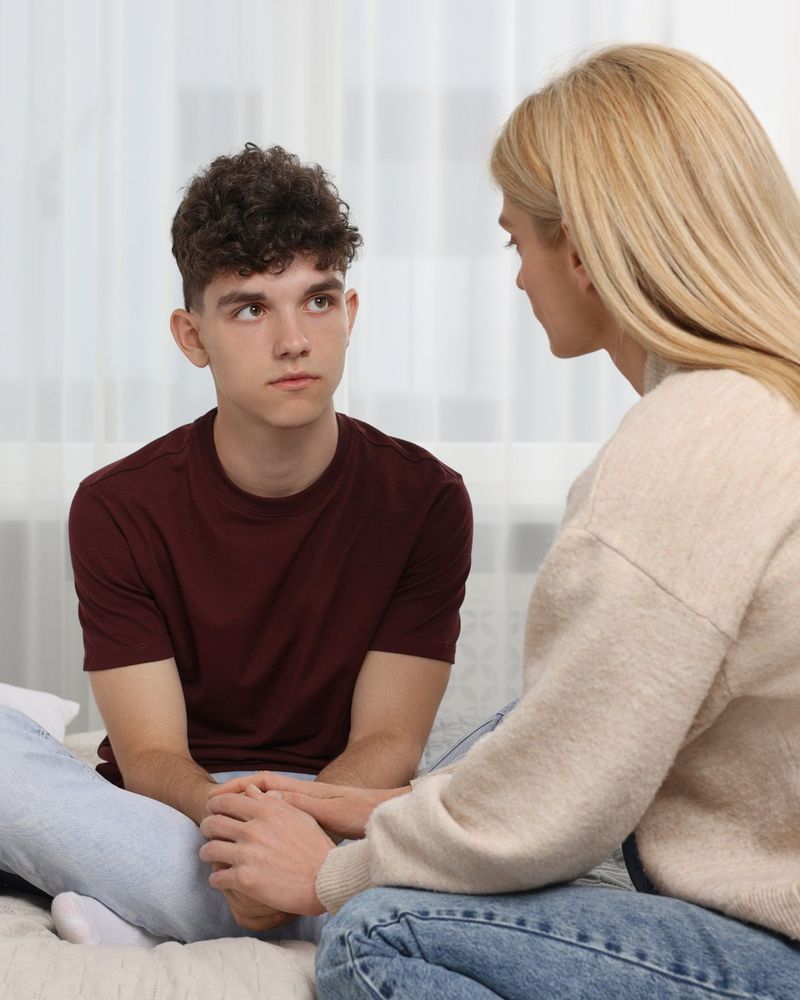 A parent speaks with their teenage child in their bedroom.


