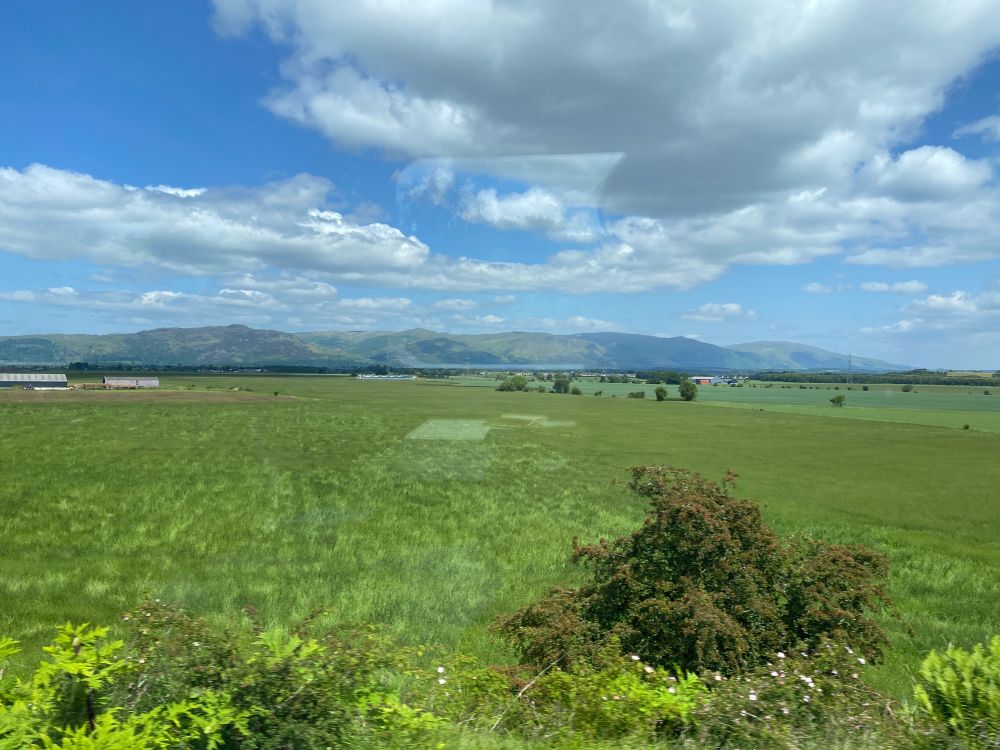 Range of steep hills in the distance across a flat grassy plain 