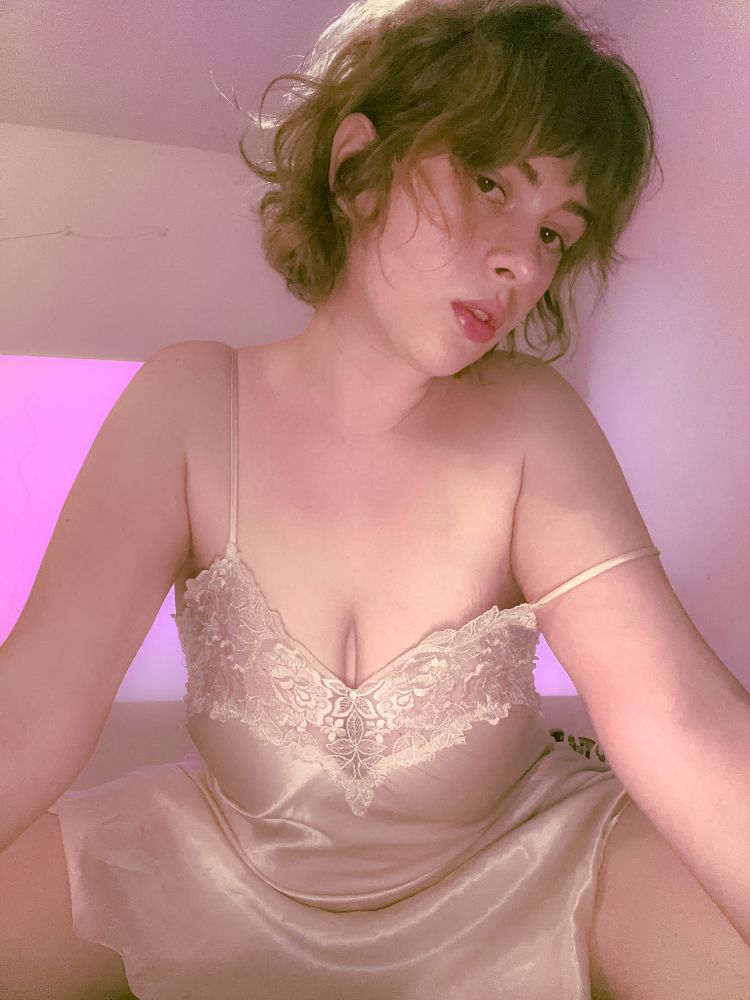 gem's looking at the camera on her knees, arms in front of her, holding herself up. mouth slightly agape. her camisole strap draped on her left arm. some upper cleavage exposed