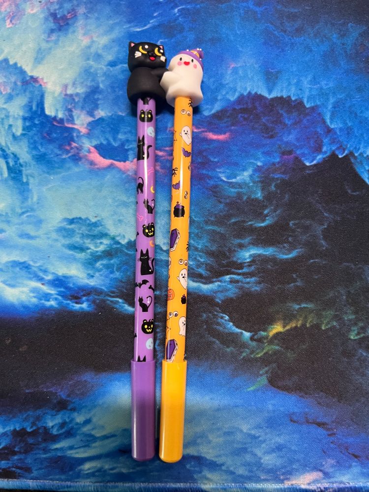 Black cat pen with purple barrel hugging a Ghost topper on an orange pen with Halloween embellishments