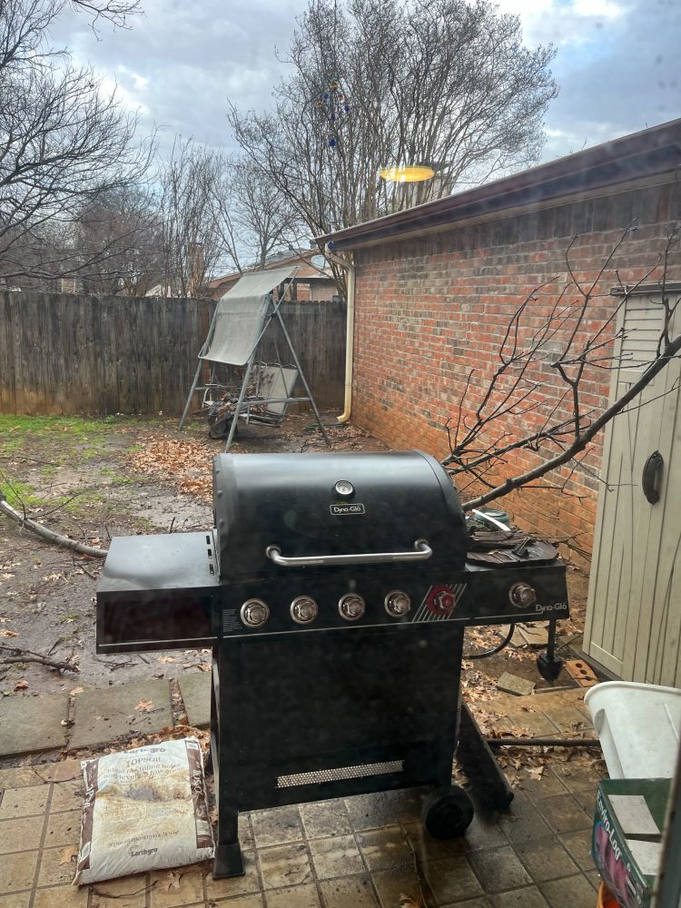 Grill with a fallen branch behind it with cloudy skies