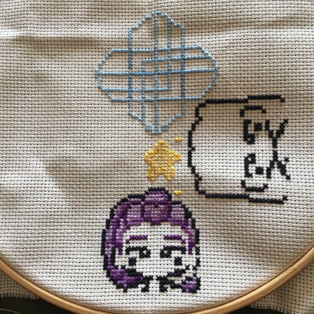 Half coloured in anime girl with star and symbol above her in cross stitch 