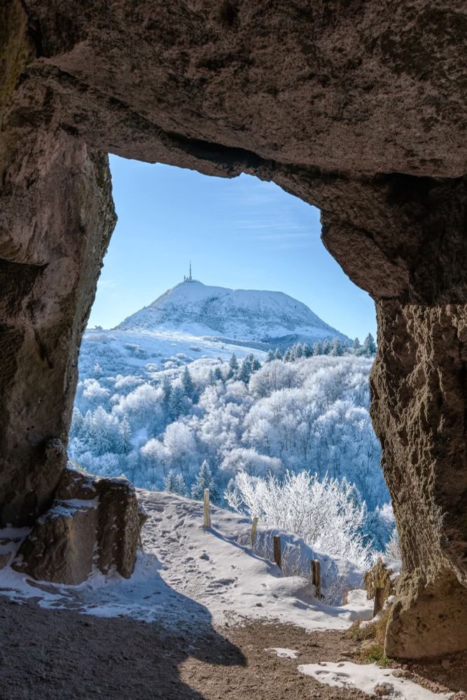 De l'intérieur d'une grotte vue sur le Puy de Dôme enneigé 