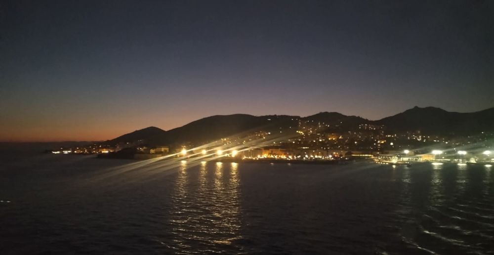 Vue nocturne sur le port avec les lumières d'Ajaccio qui se reflètent dans la mer