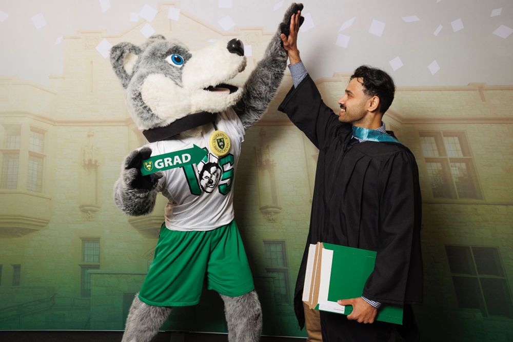 Graduates in black robes smiling at a graduation ceremony