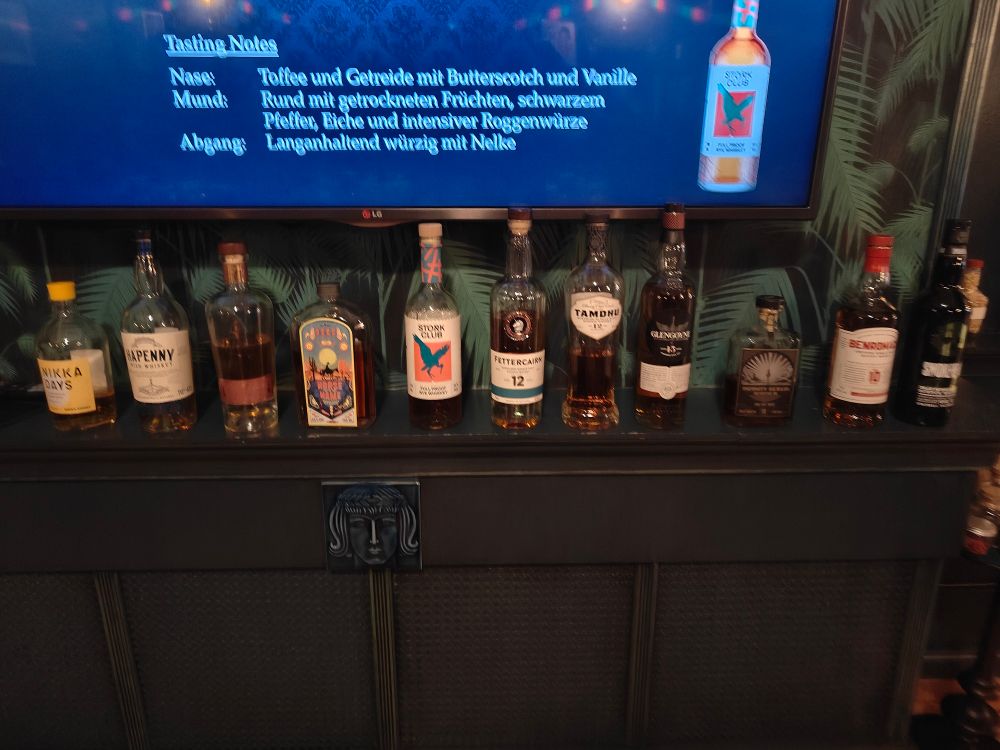 A row of 11 whisky bottles on a shelf.
