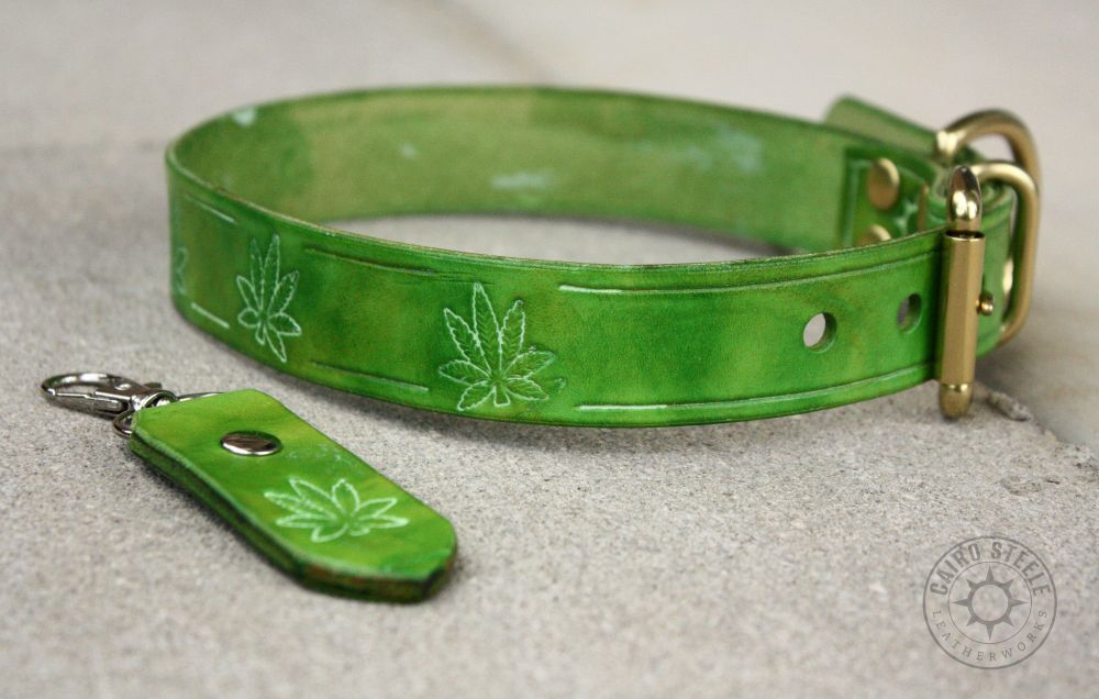 A green leather collar with hemp leaf stamps and brass hardware, with a matching keychain