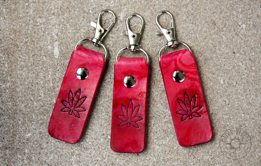 3 leather keychains in pink marble, with a hemp leaf stamped on the front. Each has a silver colored clip and matching rivet.