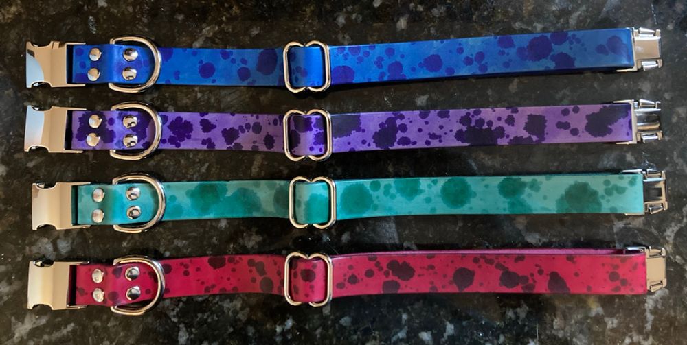 4 leather puppy collars, each a solid color with splatters in a darker shade, and with silver colored hardware. Top to bottom: blue, purple, teal, red