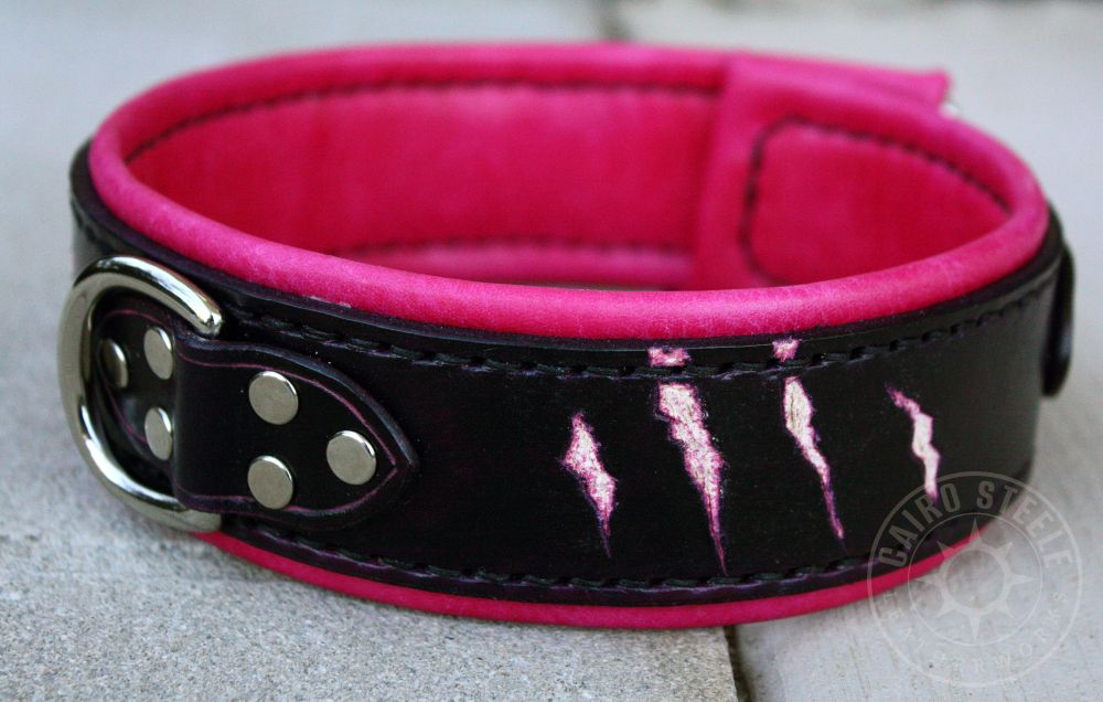 A reddish-black leather collar with raw clawmarks. It has a reddish-magenta liner, black stitching, and nickel hardware