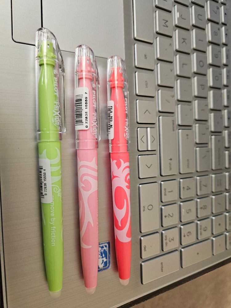 3 highlighters - light green,  pale pink,  melon - on the edge of my silver laptop