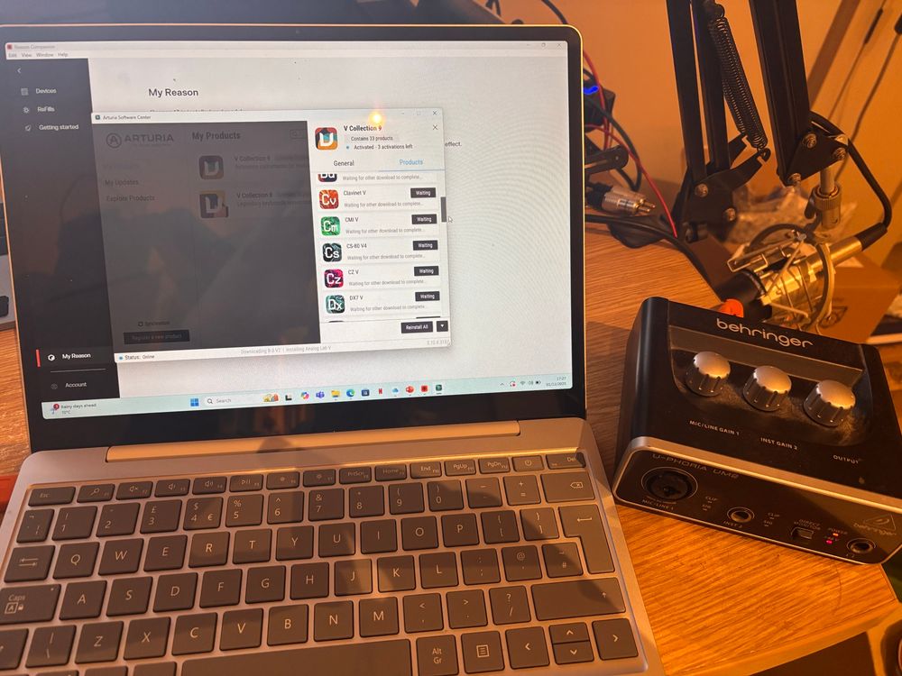 A laptop installing Reason and Arturia V Collection, next to a Behringer musicians' sound card.