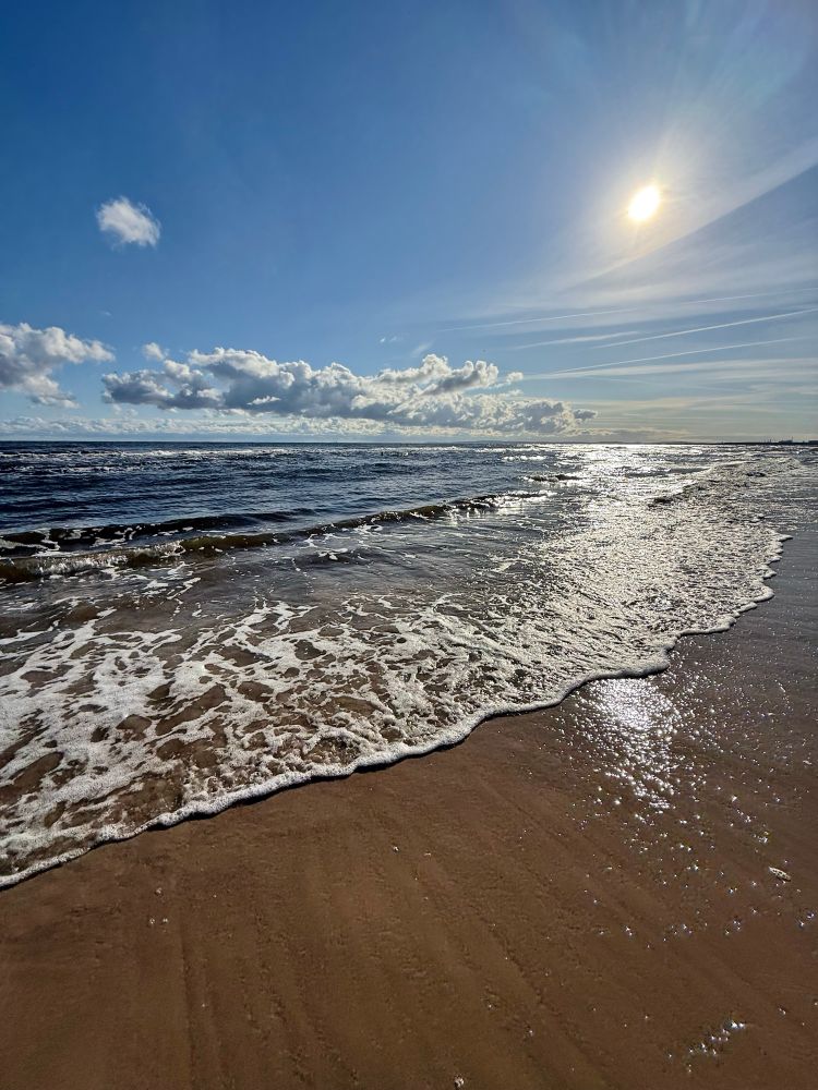 Morning at the beach, waves rolling in, sun still low.