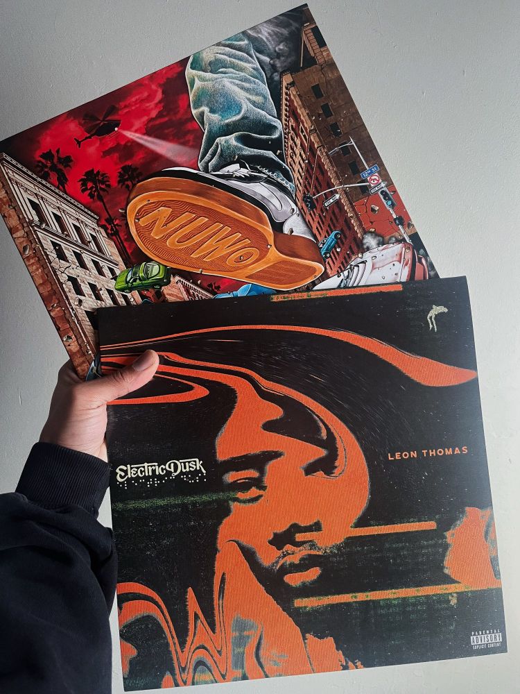 Isaac. holding up two vinyls of Larger Than Life by Brent Faiyaz & Electric Dusk by Leon Thomas.