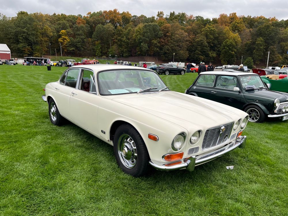 White 1972 Jaguar XJ6, next to a Mini on the Concours show field.