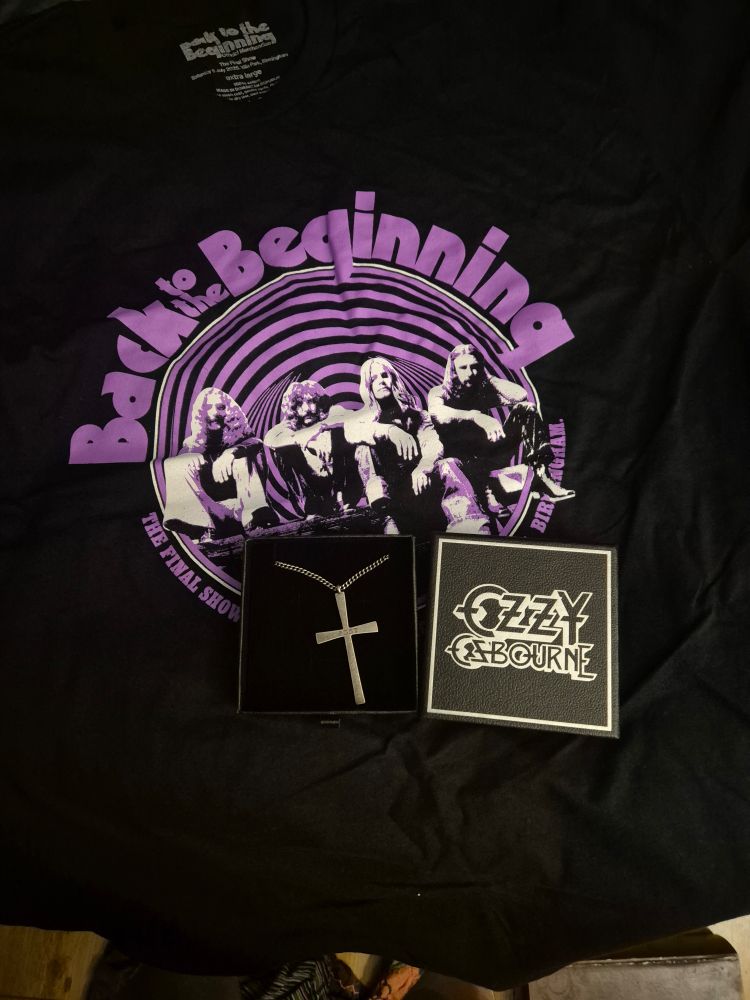 A picture of an Ozzy Osbourne "Back to the Beginning" shirt, with an Ozzy Osbourne cross pendant on top of it.