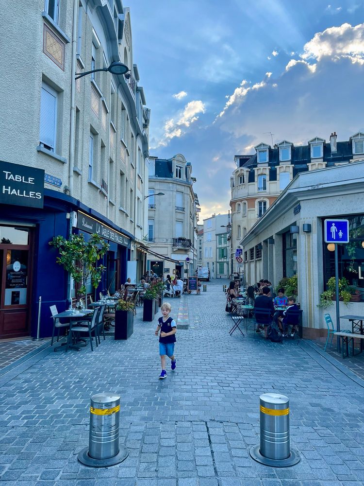 People of all ages and abilities walk, cycle, and dine along the low-traffic streets of Reims, which are lined with buildings, trees, and terraces.