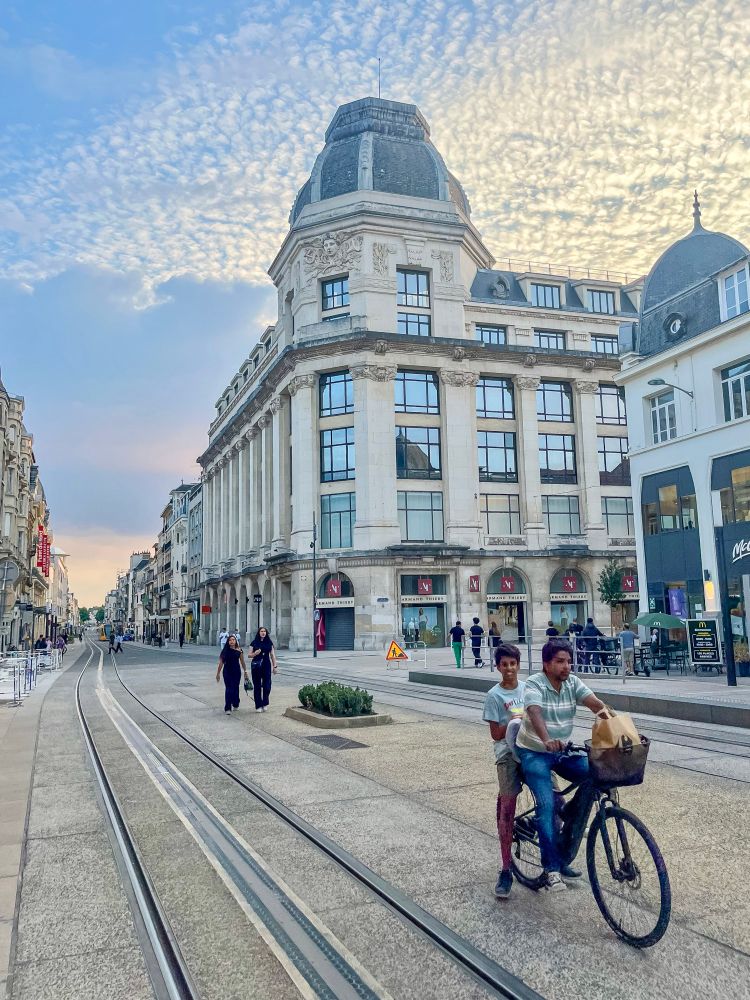 People of all ages and abilities walk, cycle, and dine along the low-traffic streets of Reims, which are lined with buildings, trees, and terraces.