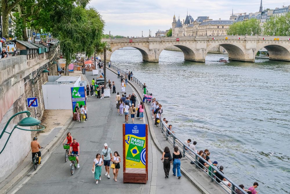 People in casual summer attire walk, cycle, lounge, drink and dine on the “Paris Plages”, an artificial beach installed along the River Seine each summer.