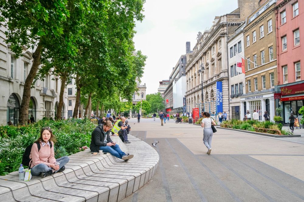 People of all ages and abilities walk, cycle, sit, and socialise on the Strand Aldwych—a former arterial turned pedestrian zone in London, which is lined with buildings, trees, flowers and plantings, benches, and terraces.