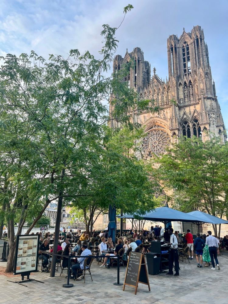 People of all ages and abilities walk, cycle, and dine along the low-traffic streets of Reims, which are lined with buildings, trees, and terraces.