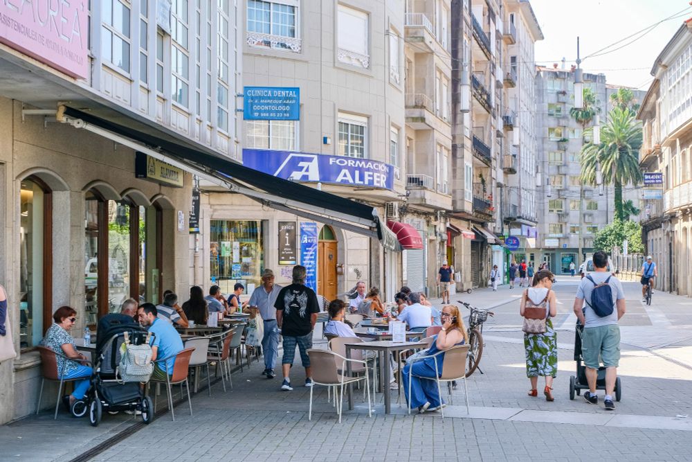 People of all ages and abilities walk, cycle, sit, and socialise on the car-free streets of Pontevedra, which are lined with buildings, trees, benches, and patios.