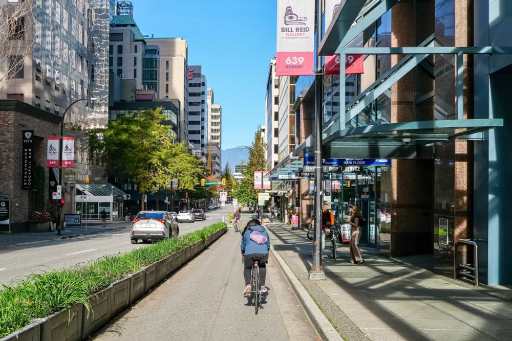 People of all ages and abilities ride bicycles on protected cycling infrastructure on the streets of Downtown Vancouver.