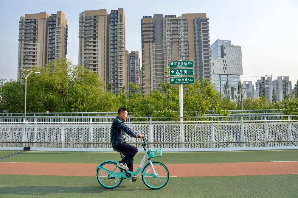 People of all ages and abilities ride bicycles along a green- and orange coloured dedicated and elevated cycle path in Beijing.