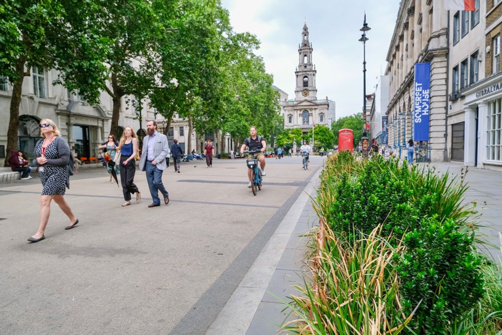 People of all ages and abilities walk, cycle, sit, and socialise on the Strand Aldwych—a former arterial turned pedestrian zone in London, which is lined with buildings, trees, flowers and plantings, benches, and terraces.