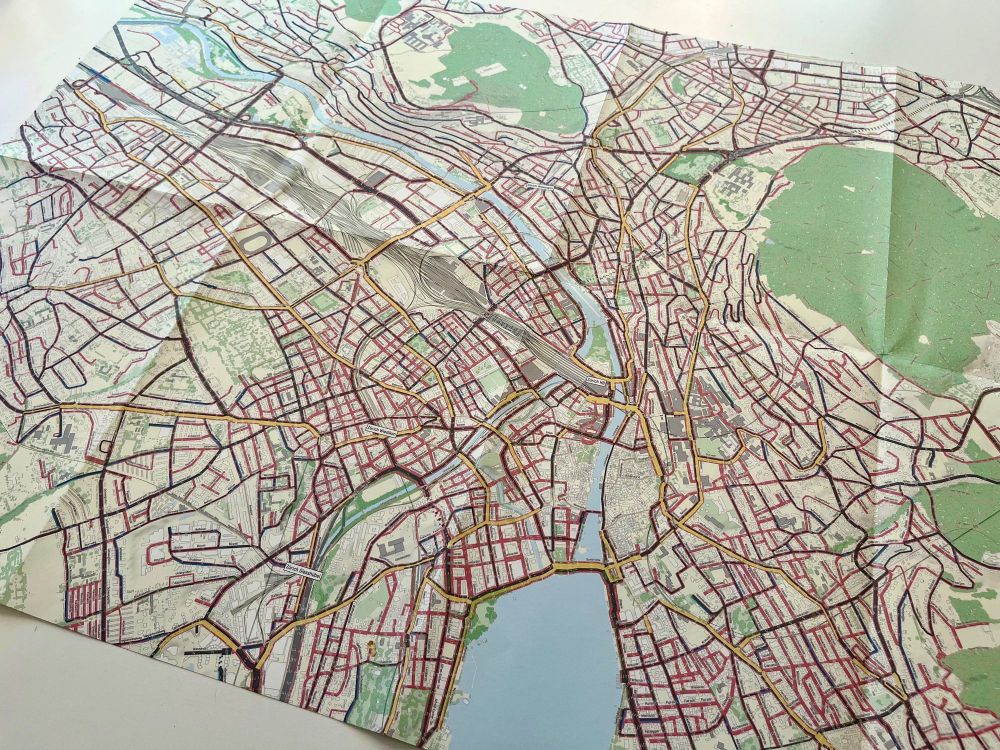Photographs of the pages of a colourful information booklet about Zurich’s “E-Bike City” project, which proposes reallocating half of its street space to pedestrians, cyclists, and public transport. 