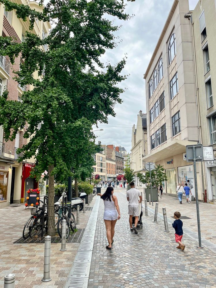 People of all ages and abilities walk, cycle, and dine along the low-traffic streets of Reims, which are lined with buildings, trees, and terraces.