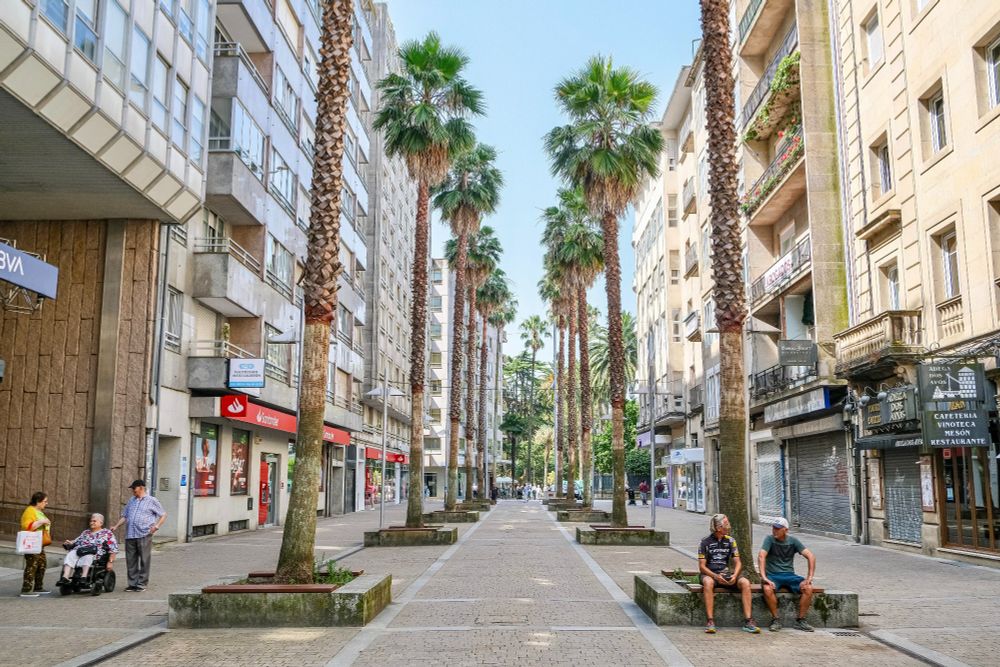 People of all ages and abilities walk, cycle, sit, and socialise on the car-free streets of Pontevedra, which are lined with buildings, trees, benches, and patios.
